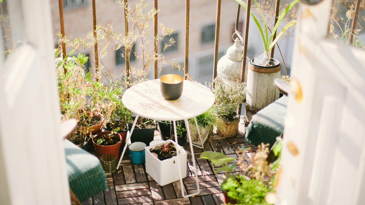Balkon z roślinami w donicach, stolikiem i kącikiem do siedzenia