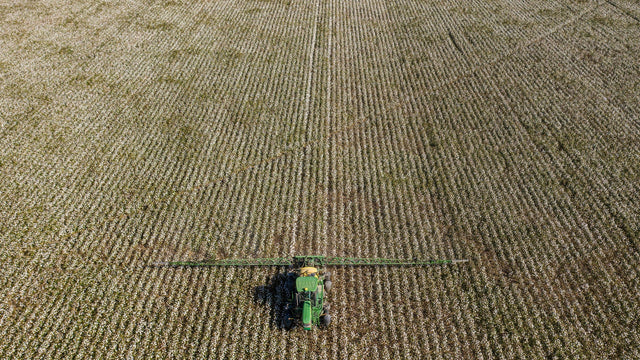 Ciągnik z opryskiwaczem belkowym na polu, widok z góry