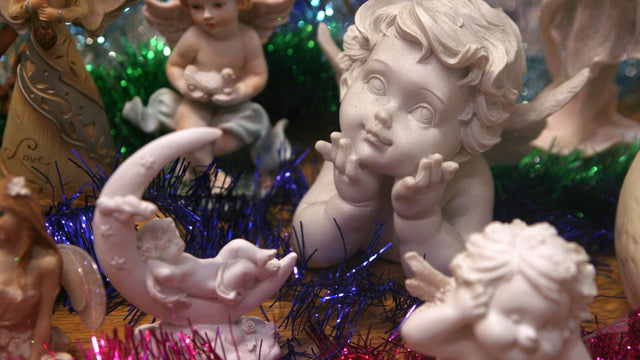 Porcelanowe aniołki i cherubiny wśród kolorowych świecidełek
