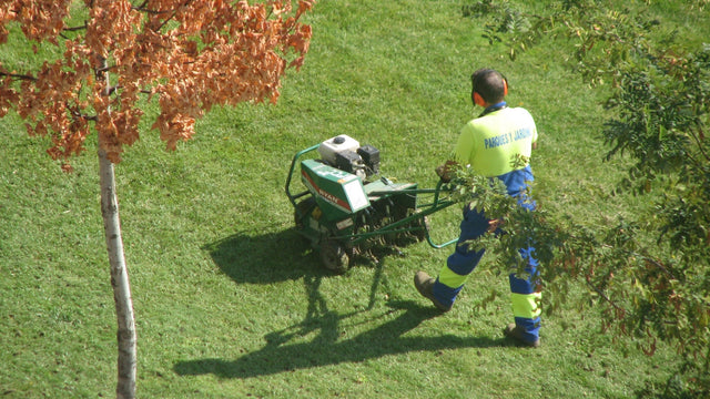 Pracownik z aeratorem na trawniku